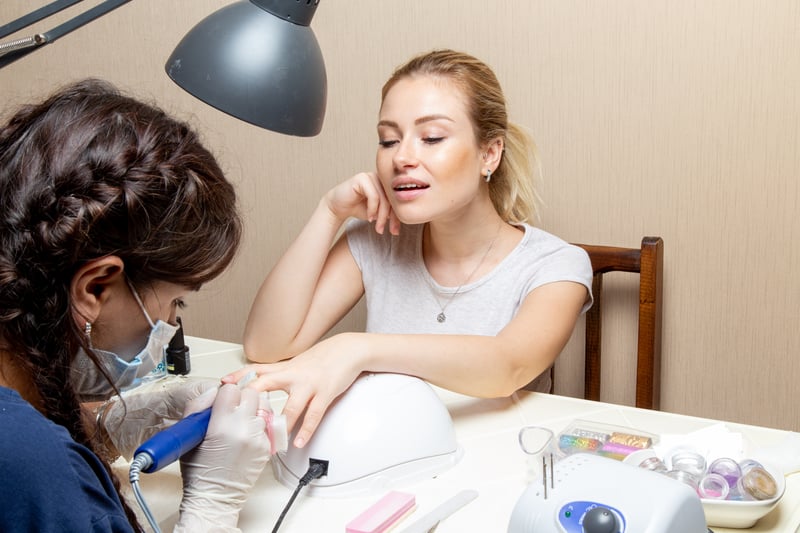 Mujer haciendose la manicura en su salon de belleza.